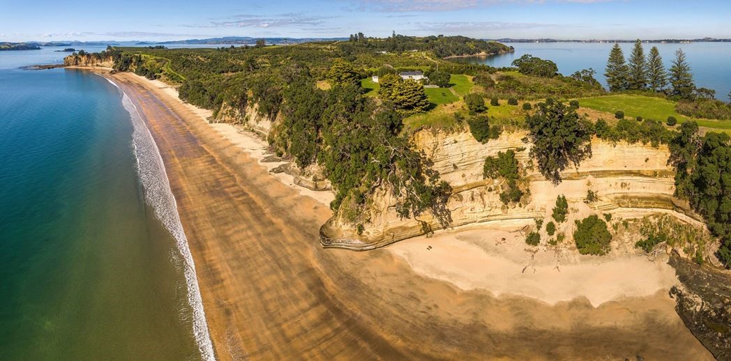 Aerial view of Motuihe Island showing golden sand beach, native bush, and the Hauraki Gulf